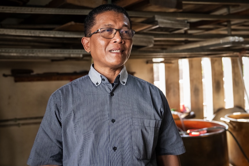 A man in a button-up shirt in a small warehouse.