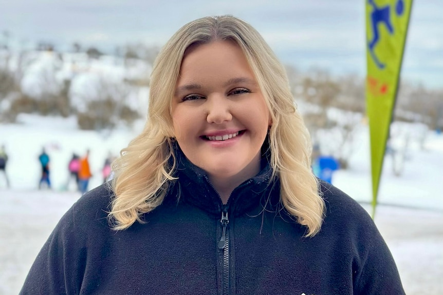 A blonde woman smiling in front of the snow