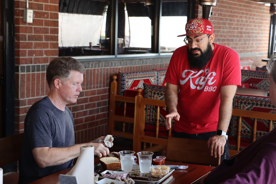 Kafi BBQ owner Salahodeen Abdul-Kafi (center) speaks with customer Jonathan Tate in Irving, Texas.