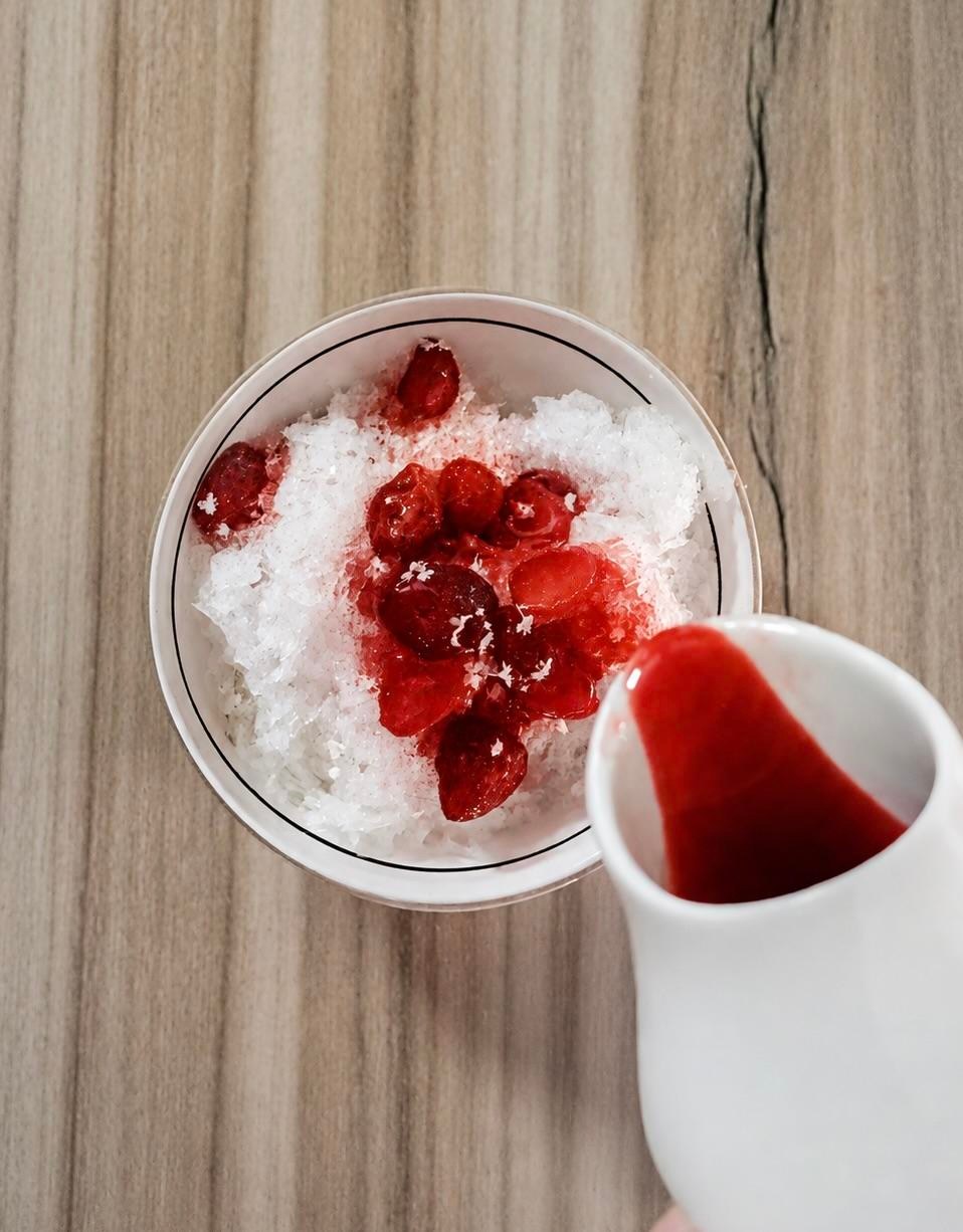 Someone pouring red liquid into a bowl of white stuff.