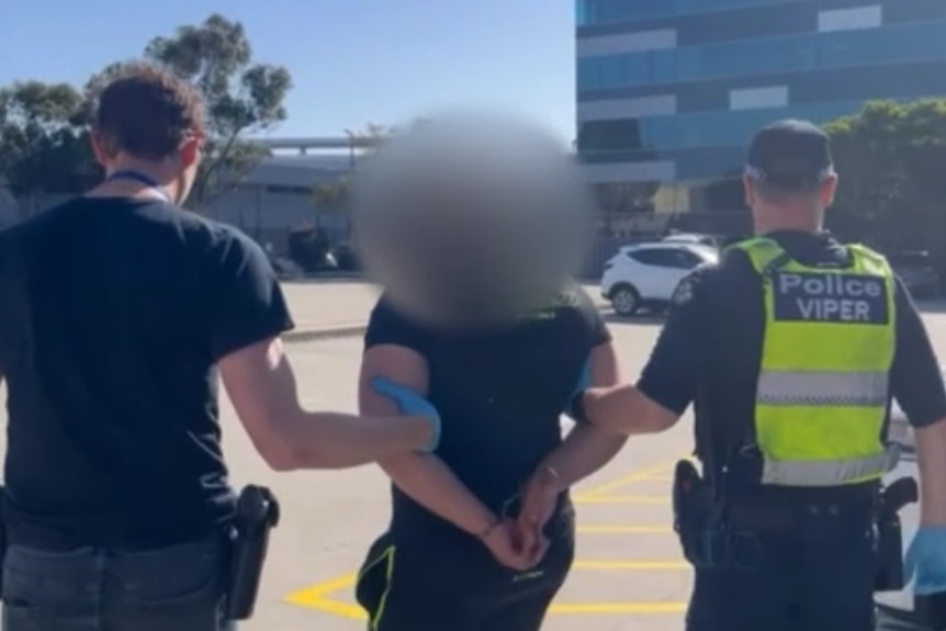 A man being led by two police officers.