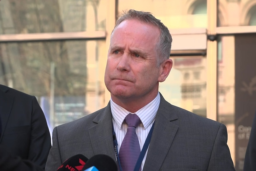 Man in a suit standing infront of court building