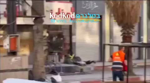 A paramedic in Jenin passing a firearm from a dead terrorist to a live one