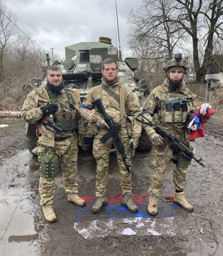 Chechen soldiers (with a Ukrainian in the middle), from the (Sheikh Mansur Chechen light infantry Battalion) of the Ukrainian Army, standing on Russian flag in front of a captured Russian armoured personnel carrier.