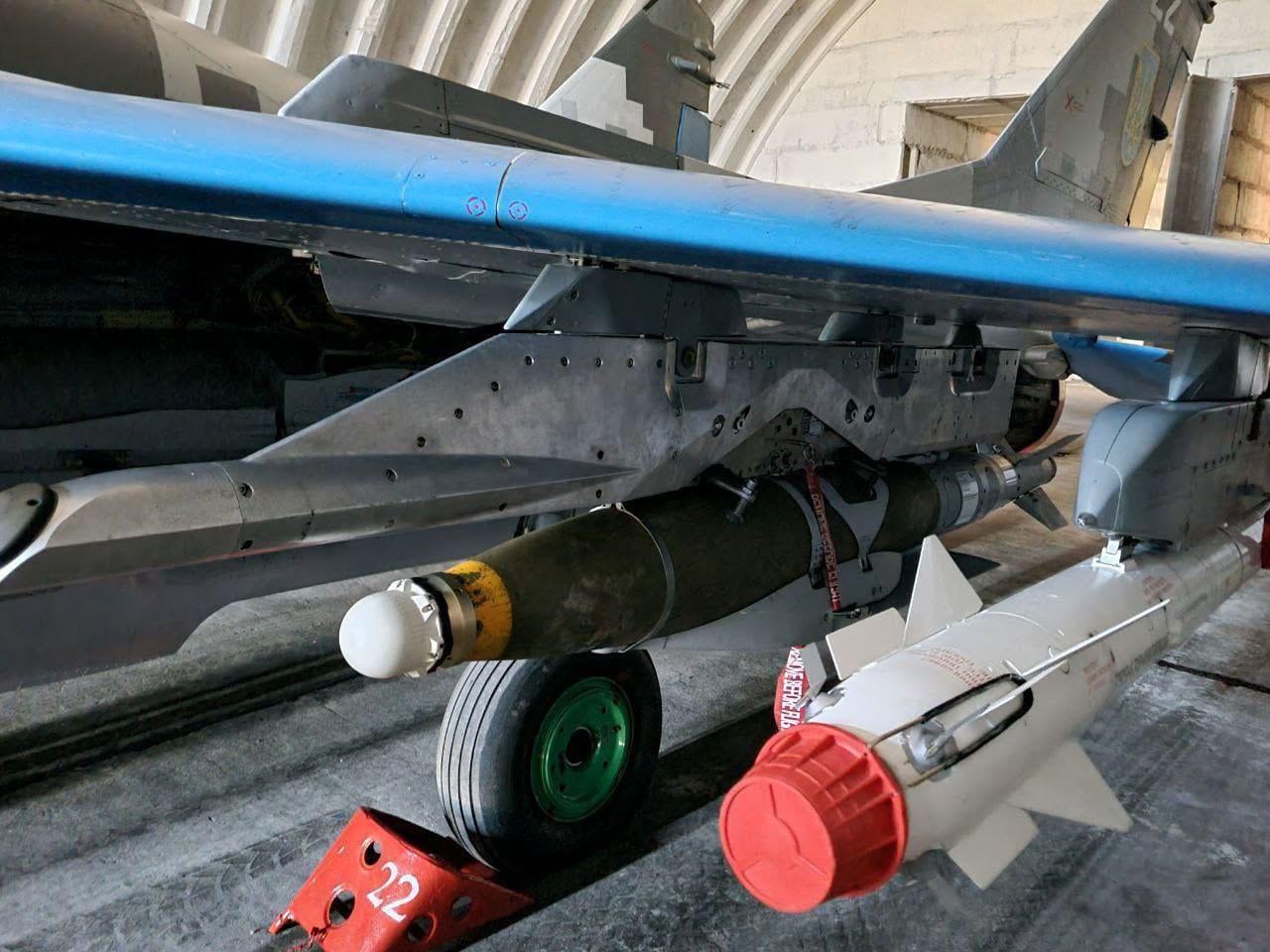 A close-up photo of a Mikoyan MiG-29 'Fulcrum' multirole jet of the Ukrainian Air Force — its armed with JDAM bomb and R-73 short-range air-to-air missile. The plane is parked inside a hangar.