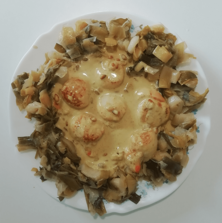 Saint-Jacques dans sa sauce au cari et lait de coco, sur une fondue de poireaux.