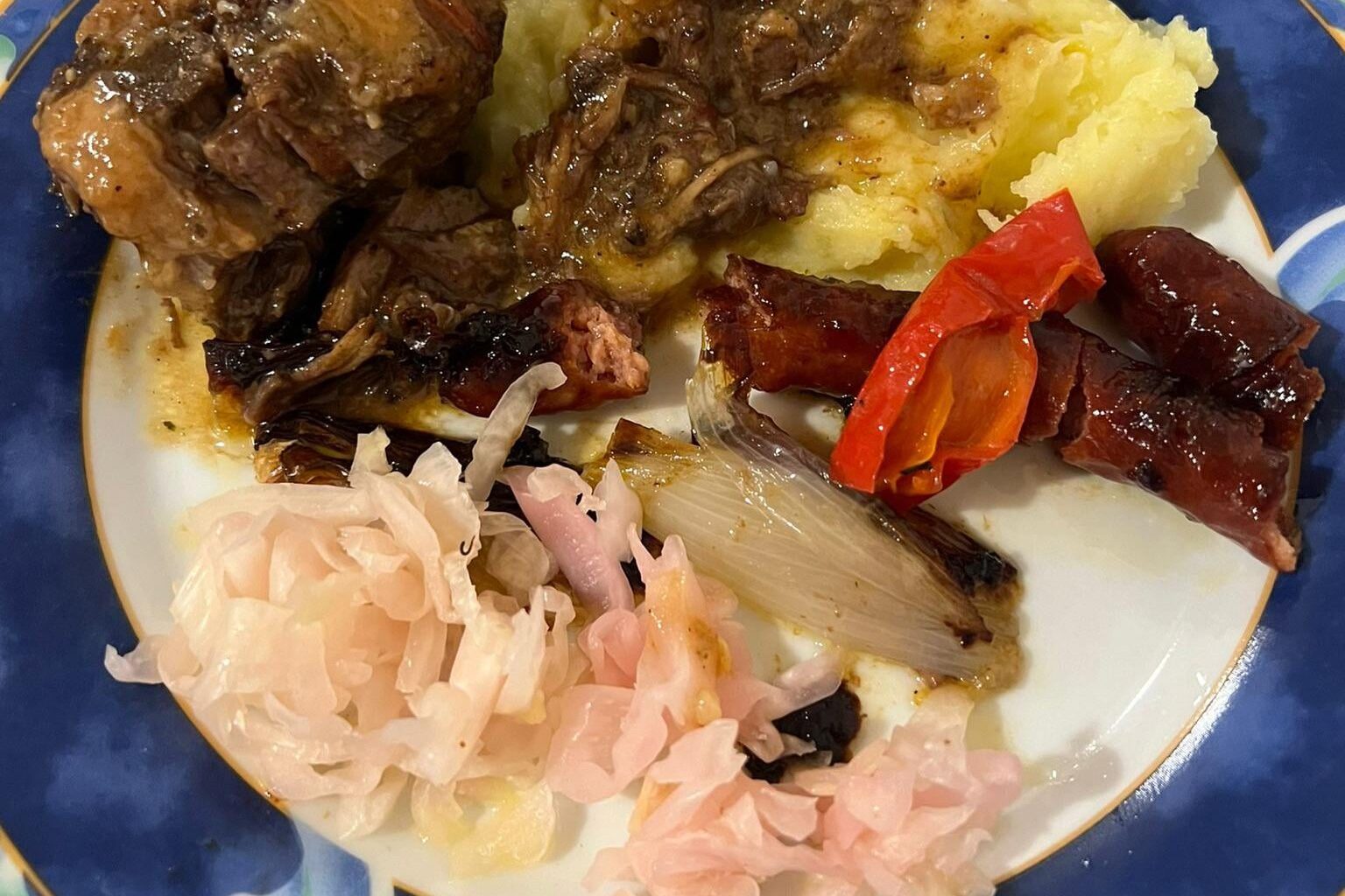 Oxtail short stew with mashed potatoes, onions and sausages plus pickled cabbage and bell peppers with olive oil.