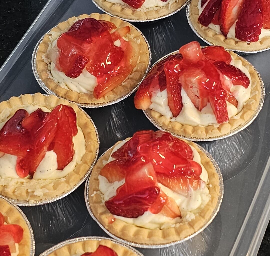 Strawberry tartlets with homemade vanilla cream in shortcrust pastry cases coated with melted white chocolate, with strawberry topping cake glaze