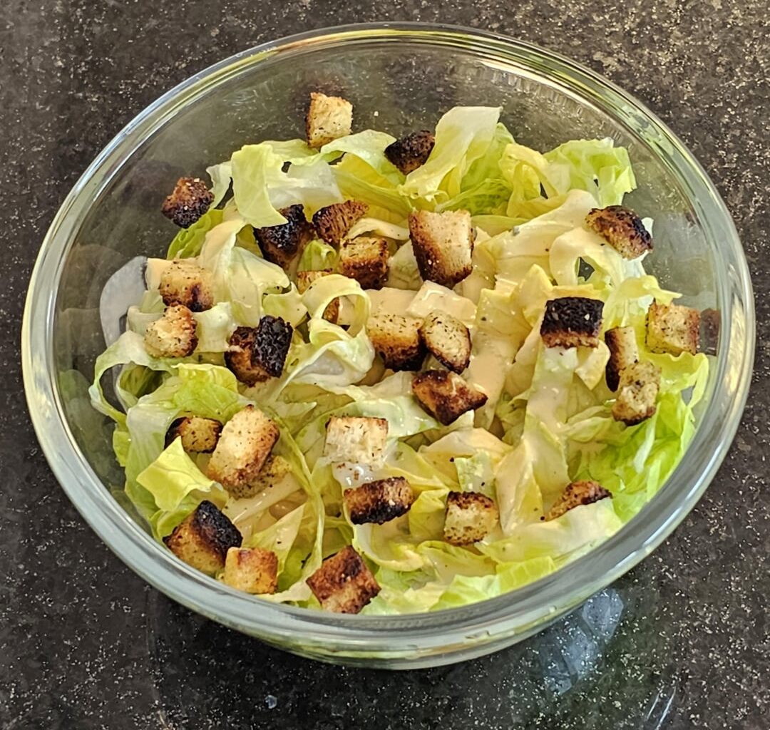 Simple salad with olive oil, ground pepper and freshly prepared croutons