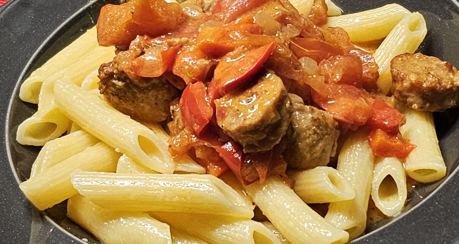 Penne with meatballs made from coarse pork sausage in a creamy red wine sauce with onions, paprika, and peppers
