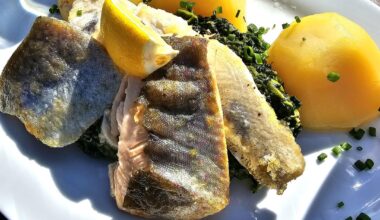 Fillets of zander, trout and char with spinach and boiled potatoes, served on today's sunny day in spring on the island of Reichenau, Lake Constance, Germany