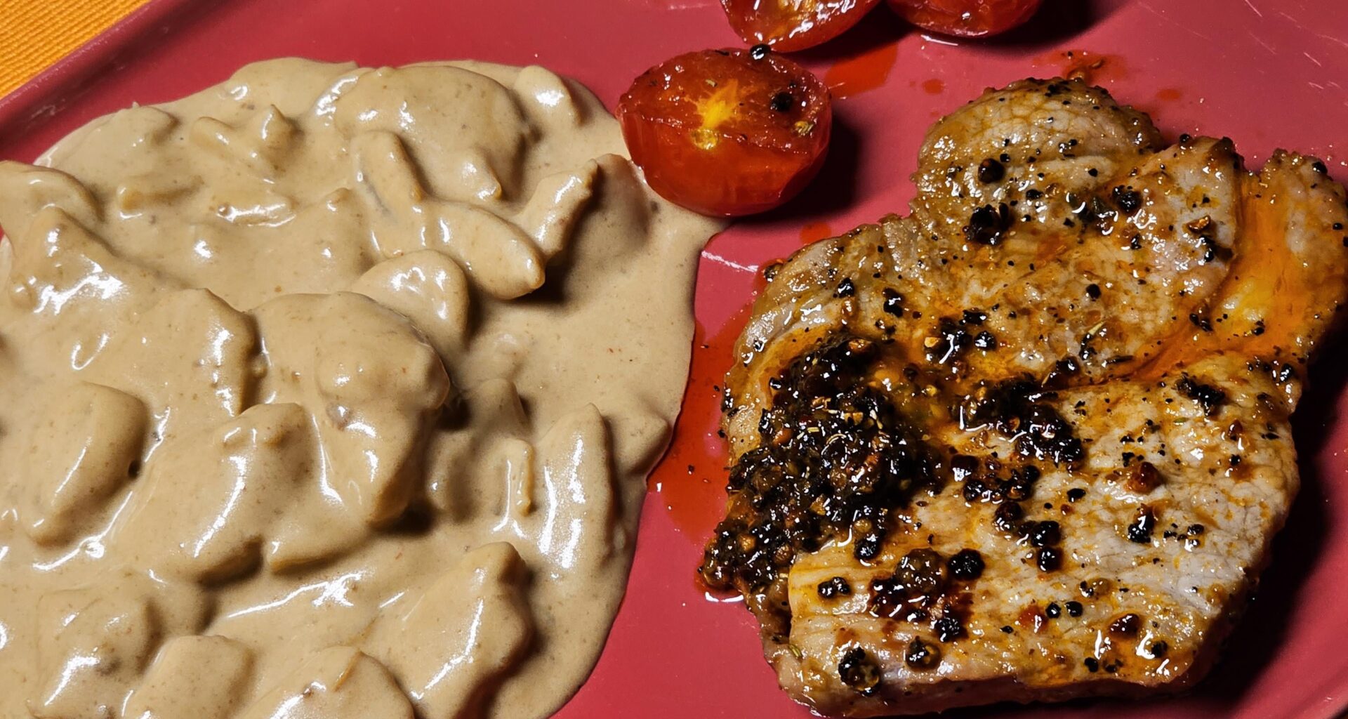 Steak with potato salad, grilled halved cocktail tomatoes, and homemade herb butter
