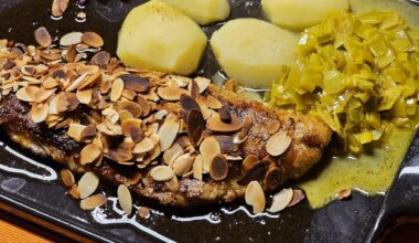 Fried fillet of pike-perch with roasted almonds in a lemon-butter sauce, with leek in a curry-white wine sauce, boiled potatoes and red radish sprouts