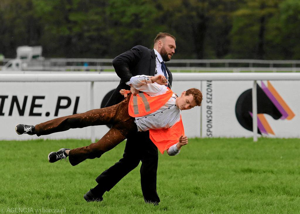 Guard carries out a climate activist who wanted to interrupt a horse race in Służewiec with orange paint, which he spilled on himself.