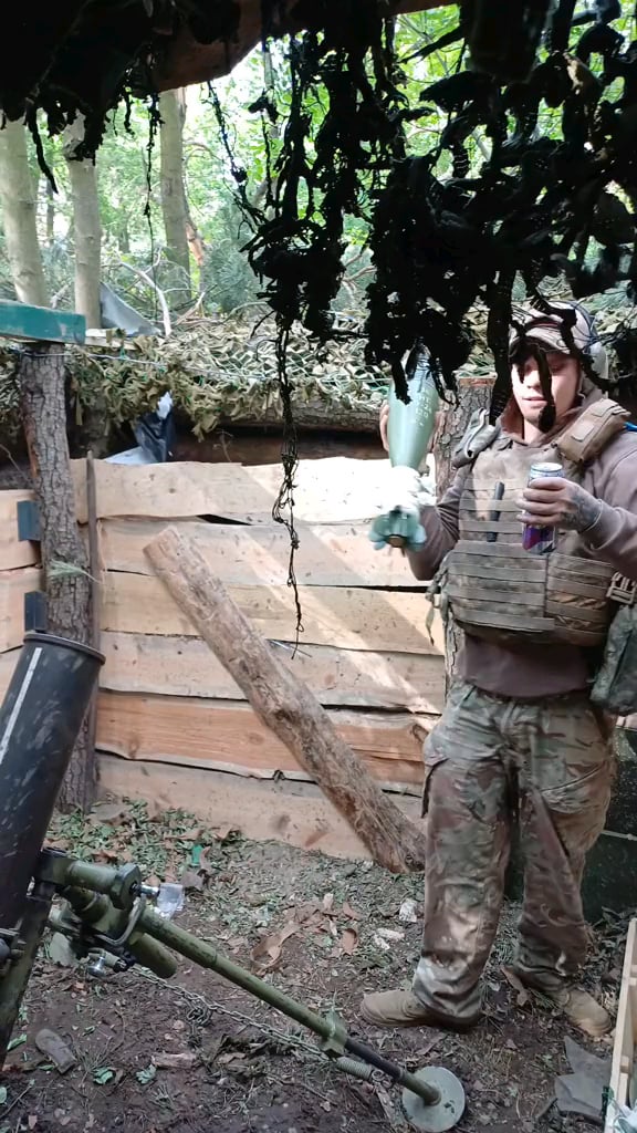 Ukrainian soldier firing 120mm mortar from camouflaged position dug into the ground with movable roof. Bureviy Brigade. Forest in the Kreminna region. May 2024