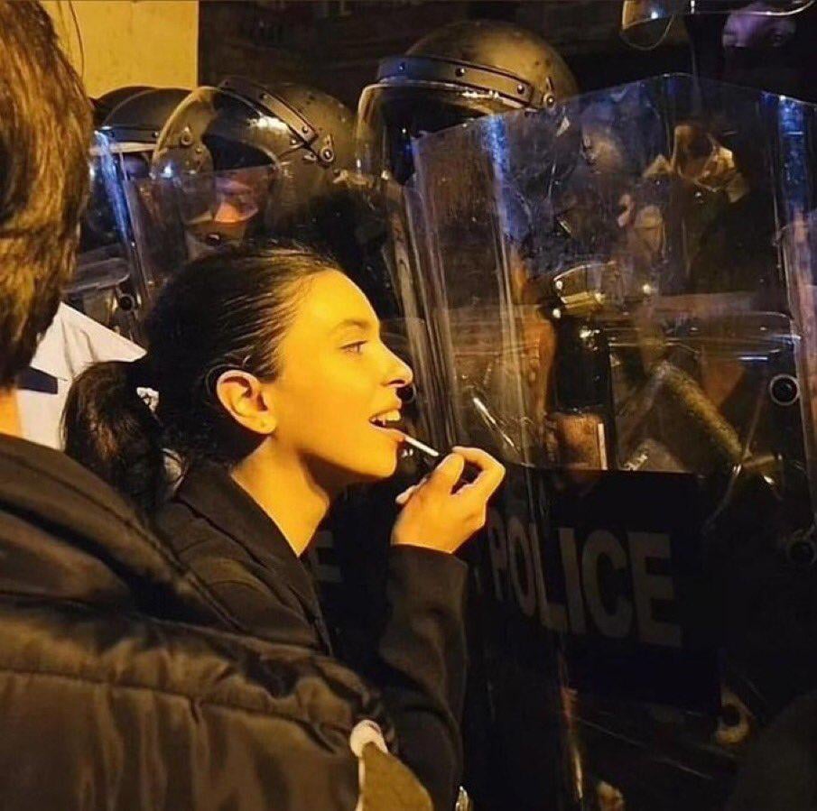 Georgian pro-EU protester makes use of the riot police sent in to disperse the protesters