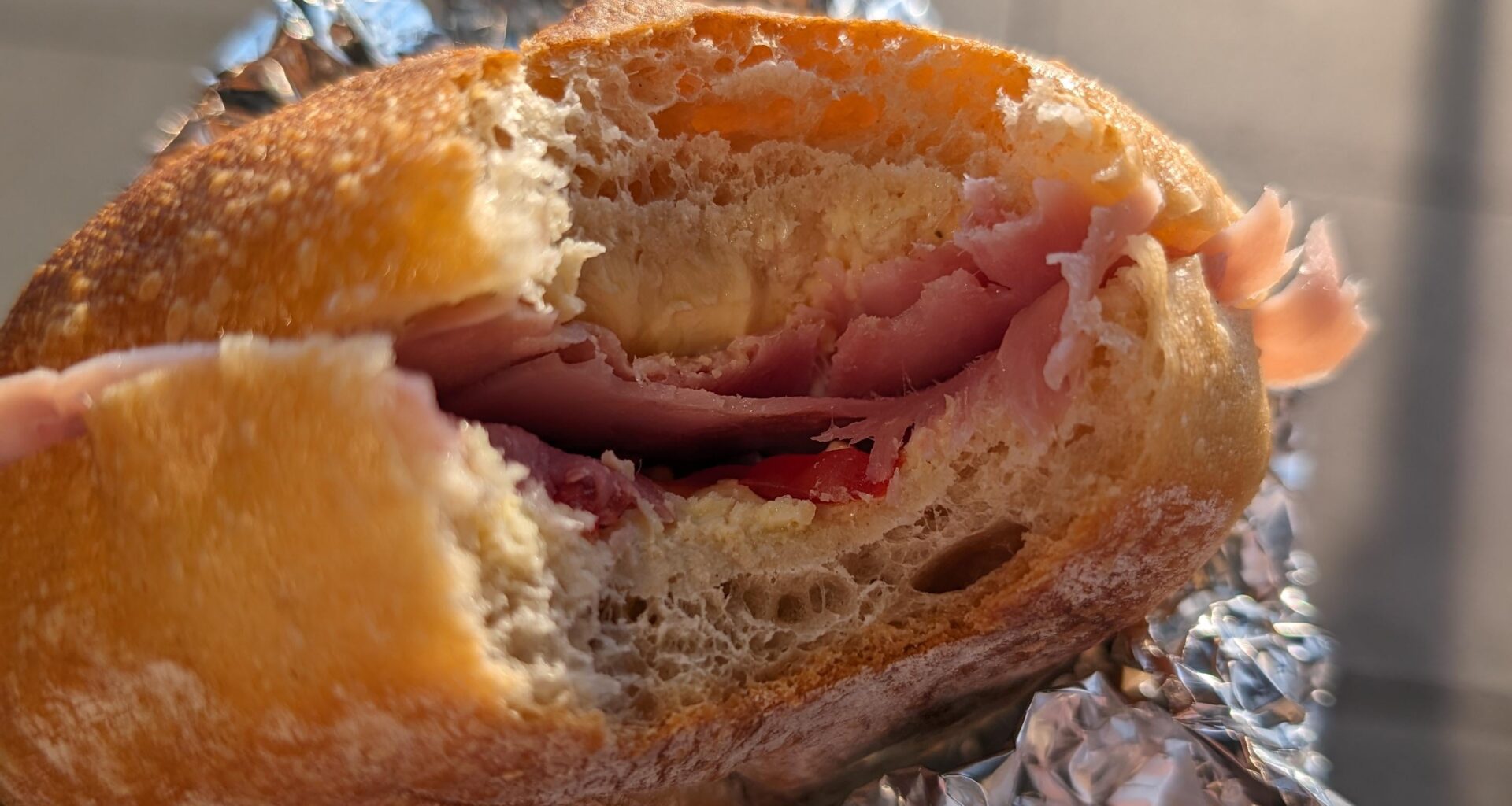 Homemade bread roll with cherry tomatoes and prosciutto cotto.