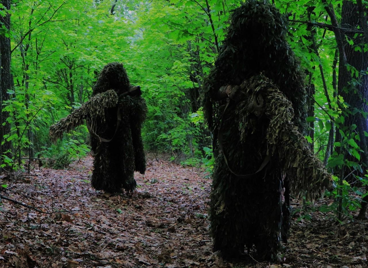 Snipers in ghillie suits, walking through a forest - they are from the (22nd Mechanized Brigade) of the Ukrainian Army.