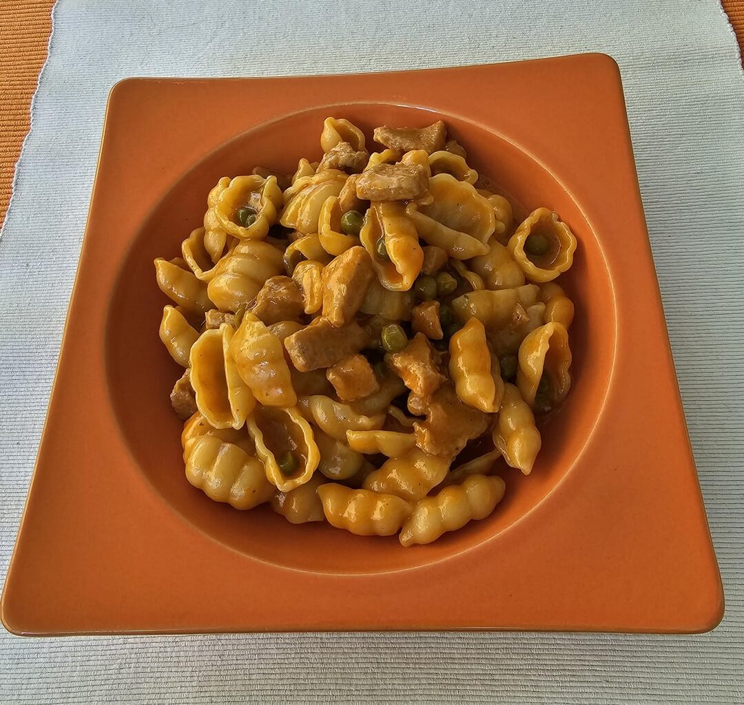 Pasta with small pieces of raw veal sausage meat rolled in potato flour, sautéed with onions, then cooked with tomato puree, peas, spices and plenty of white wine, flavoured with cream