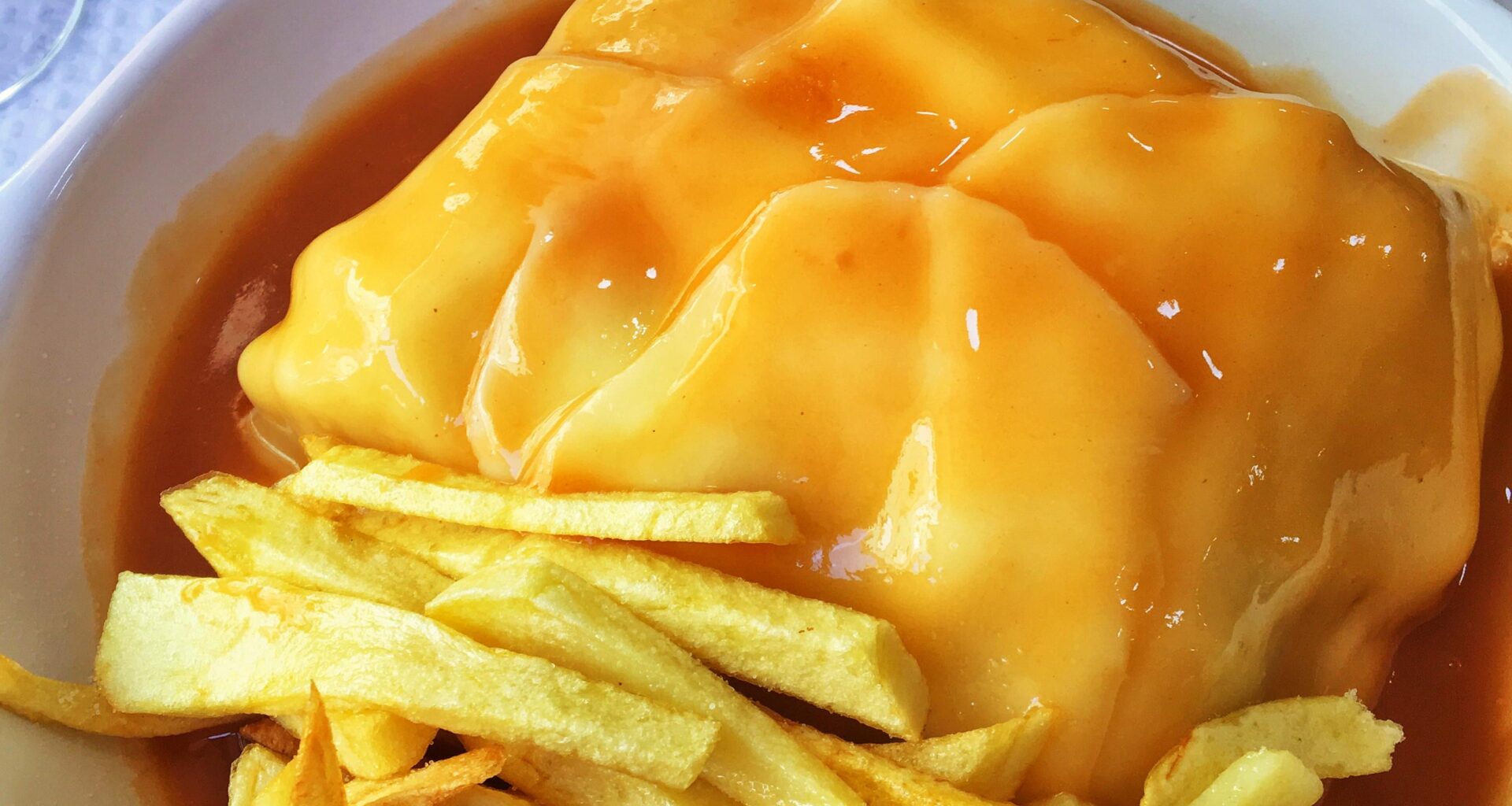 Francesinha (Portugal) - technically a sandwich, with all kinds of deli meats, covered in cheese, an egg and accompanied by fries/crisps and hot sauce!