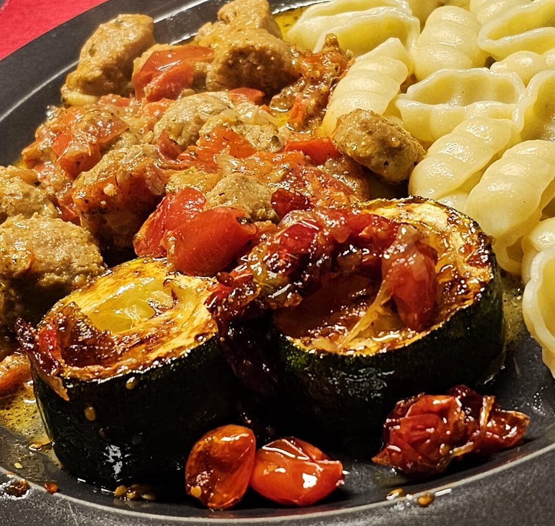 Meatballs from row pork sausage, at a spicy and creamy sauce, with fried courgettes and pasta