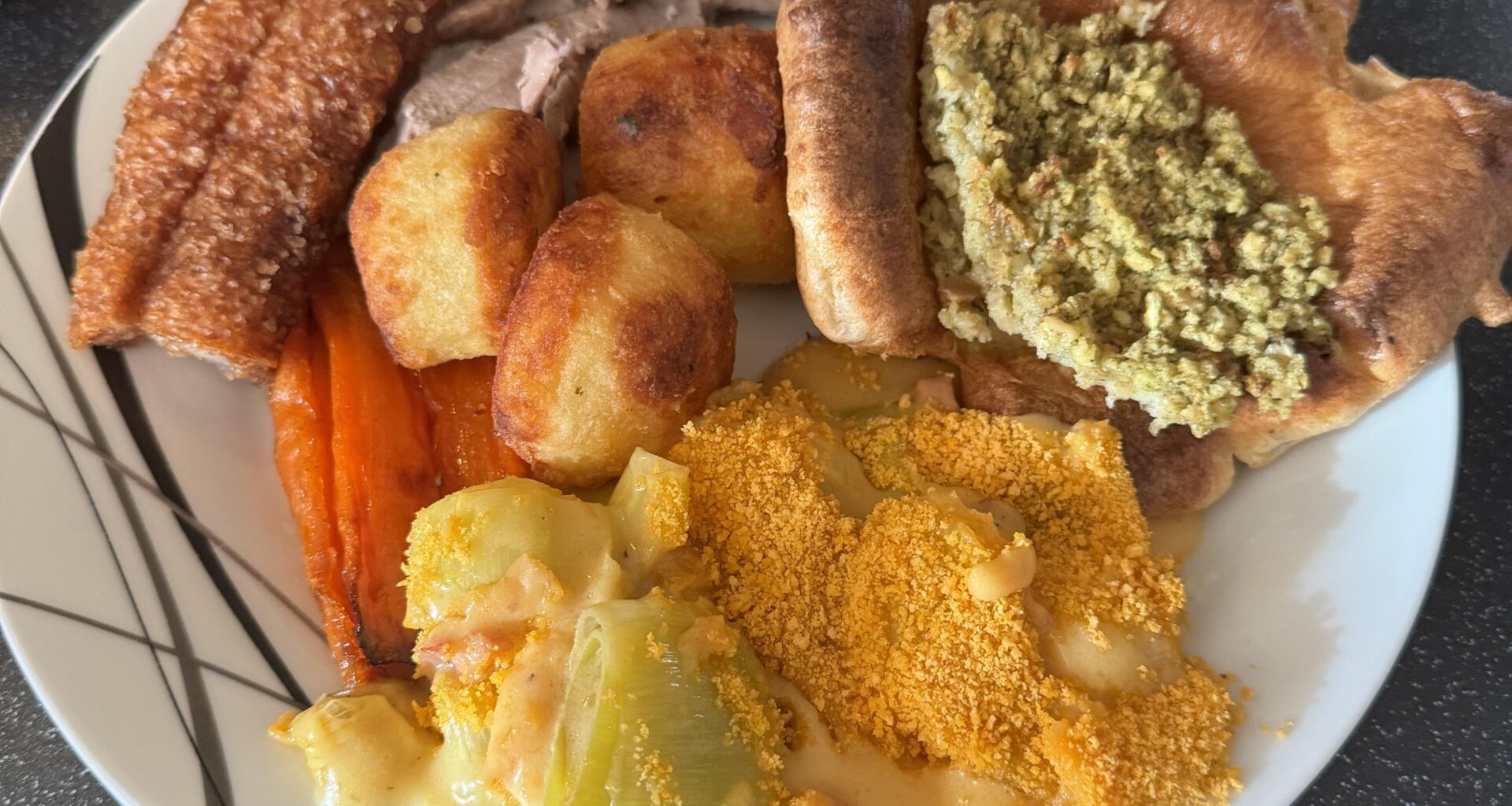 Roast pork dinner with Yorkshire pudding, cauliflower cheese, honey roasted carrots, stuffing and roast potatoes