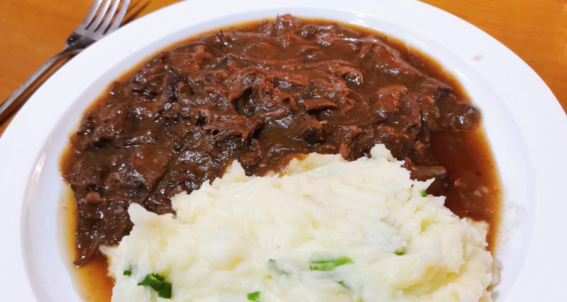 Slow cooked pork cheeks ragout with creamy scallions mashed potatoes and sautéed Chinese cauliflower on the side