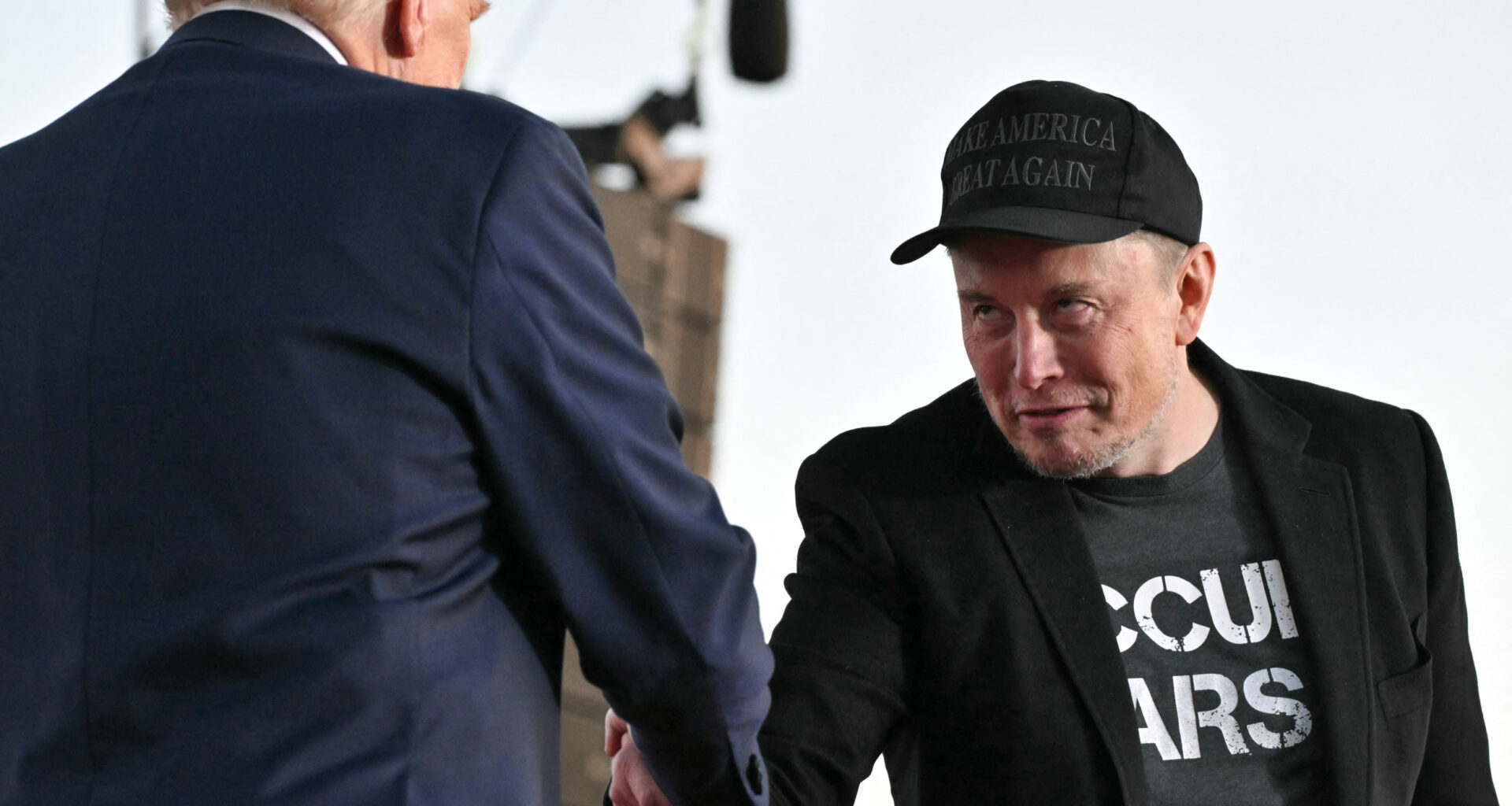 Donald Trump and Elon Musk shake hands.