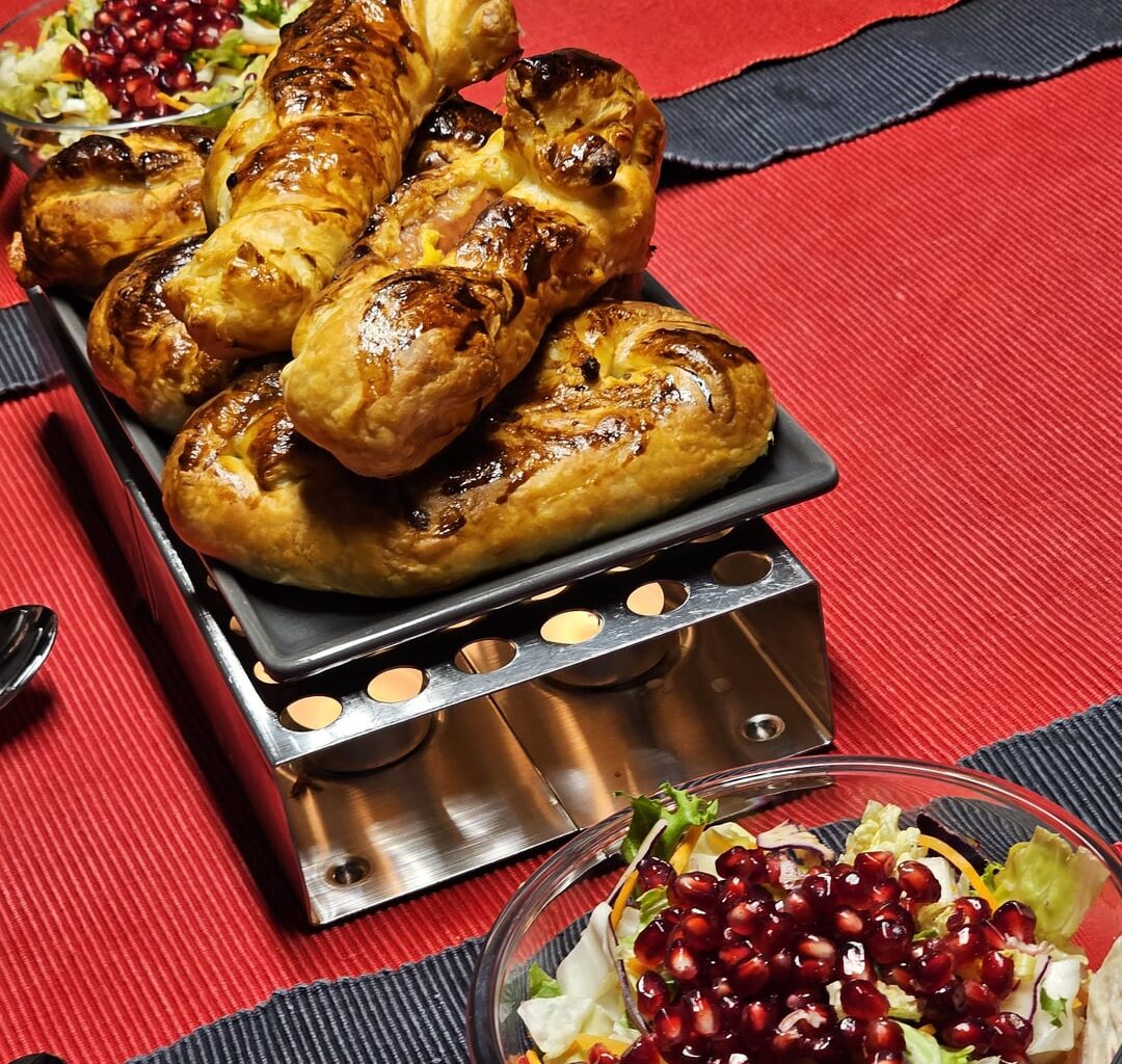 Homemade sausage rolls made from puff pastry and original Emmental cheese sausages ("orig. Emmentaler Käsewürstli") with a cheese and tomato filling (the cheeses were savoury Appenzeller and Gruyère), along a salad with pomegranate seeds