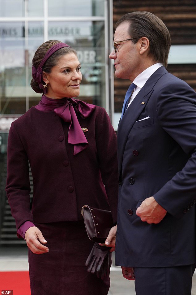 Victoria, 47, accessorised her outfit with a burgundy leather clutch bag embellished with silver studs
