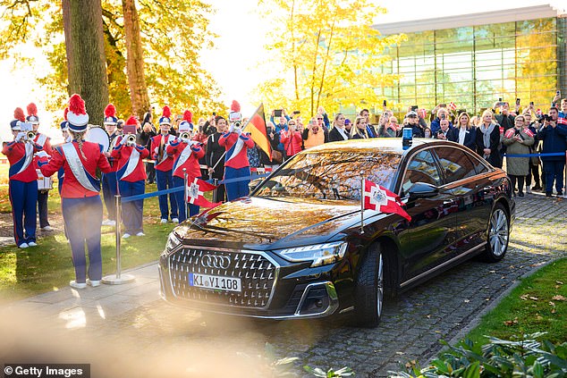The Danish royal couple arrive in a blacked out Audi adorned with Danish flags as a marching band dressed in red, white and blue played to welcome them