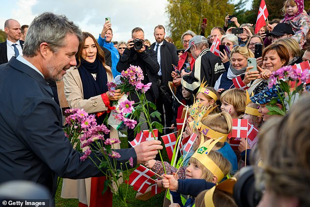 With a wide smile across his face, King Frederik looked truly delighted to receive flowers from children waving Danish flags
