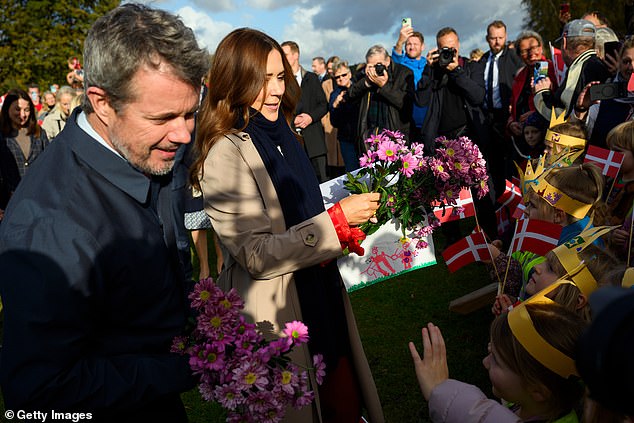 Queen Mary and King Frederik greeted royal fans waving Danish flags. Both royals received bouquets of pink flowers while Mary signed a card