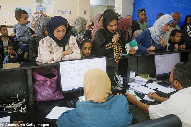 Palestinians wait in a queue at a UNRWA clinic in Deir-al-Balah to receive medication and medical treatment