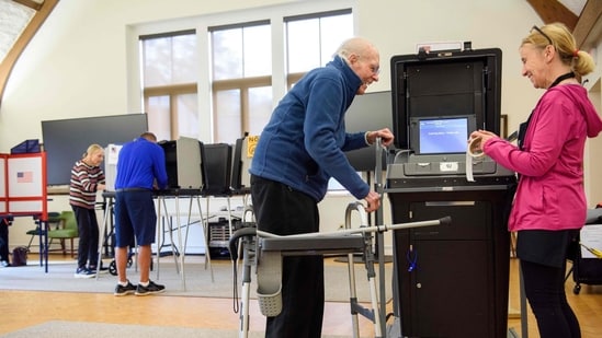 US Election 2024 Live: A poll worker offers a voting sticker to a voter US Election 2024 Live: A poll worker offers a voting sticker to a voter