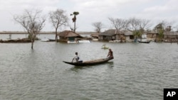 FILE - In this photo taken May 14, 2010, a villager rows a boat past the cyclone-affected Gabura village, in Bangladesh.