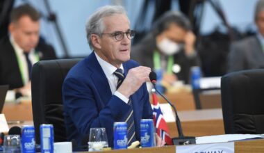 Statsministeren sitter ved et ovalt møtebord, har ordet og holder innlegg.