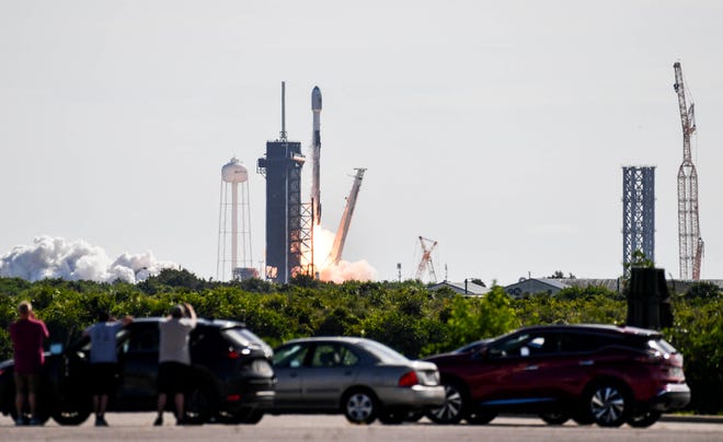 A Falcon 9 rocket launches next to a Starship Super Heavy launch tower (to the right) under construction on July 24, 2022 at Kennedy Space Center's Pad 39A. Currently, the new launch tower stands tall on the historic Florida launch site, where multiple Starships may be launched as part of NASA's Artemis Program.