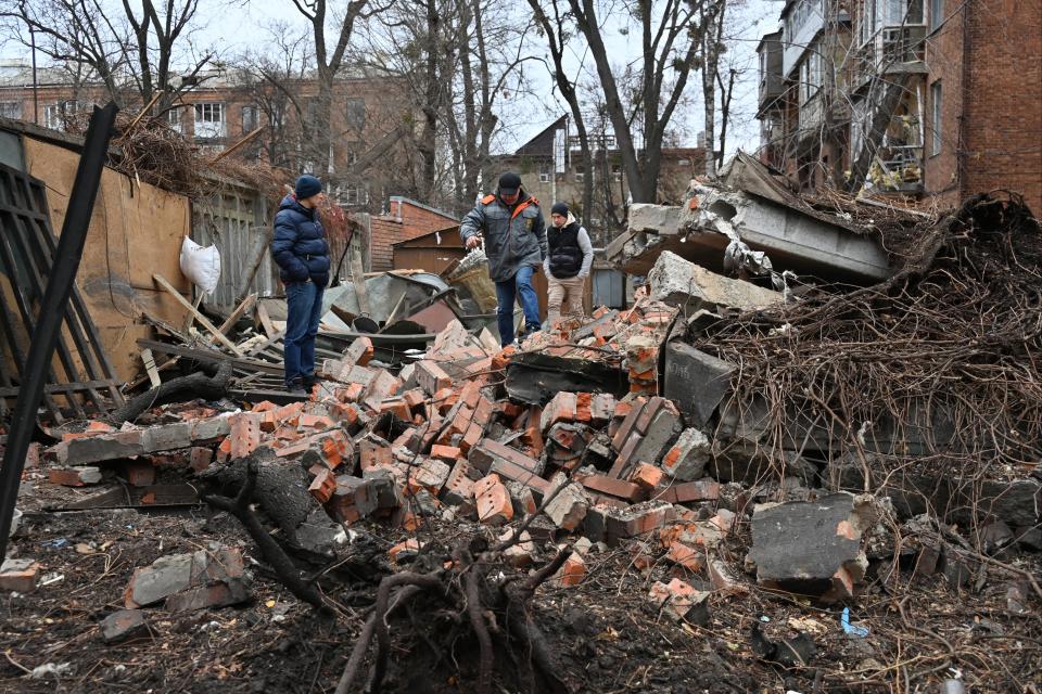 Local residents walk among debris in the courtyard of a residential building following a missile attack in Kharkiv (Sergey Bobok/AFP via Getty Images)