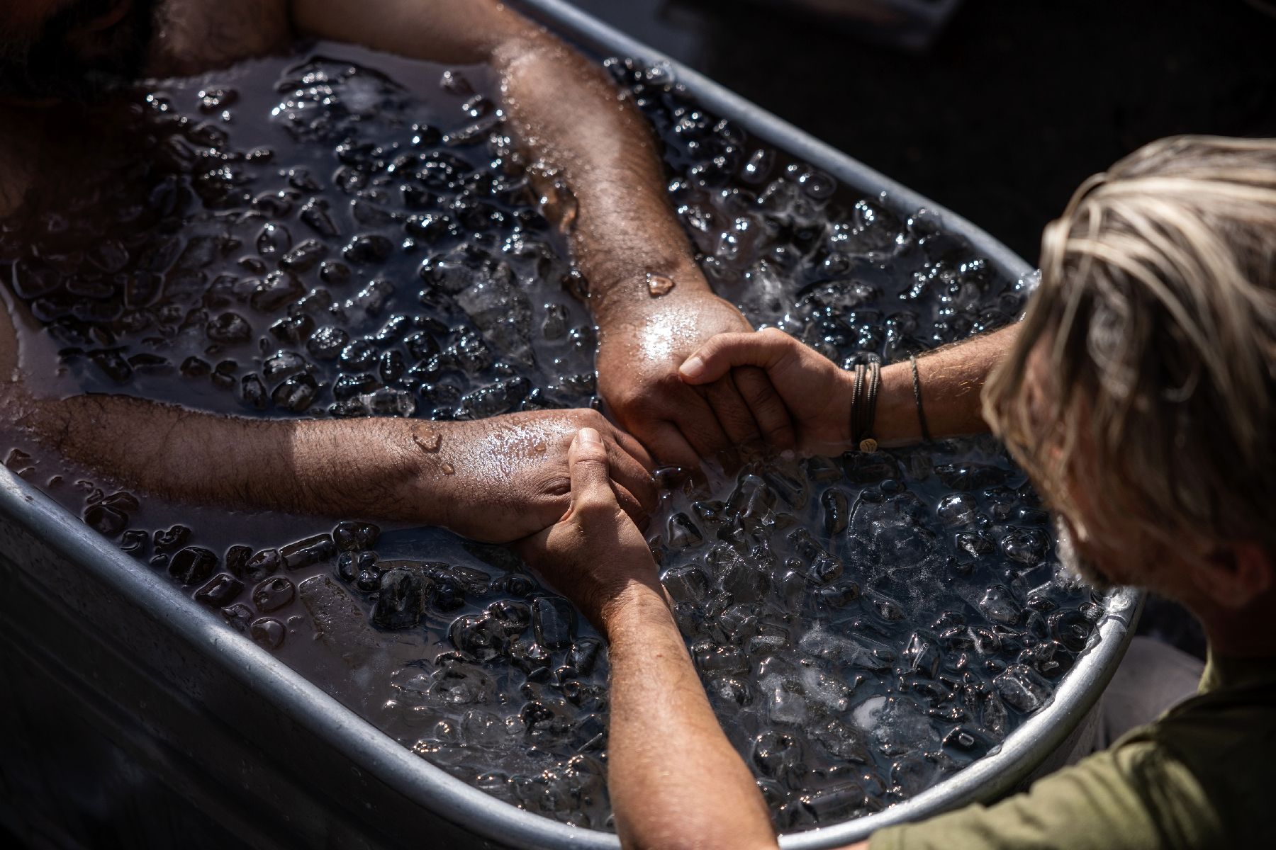 Un volontaire de Zaka immergé dans une baignoire métallique remplies d'eau froide et de glace, est guidé par un thérapeute (d) lors d'une session d'activités visant à traiter les traumatismes, à Nes Harim, près de Jérusalem, le 17 novembre 2024