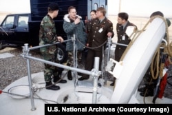 A U.S. Army interpretor translates for Russian Strategic Rocket Forces colonels at the entrance to an access shaft into a Minuteman III nuclear missile silo.