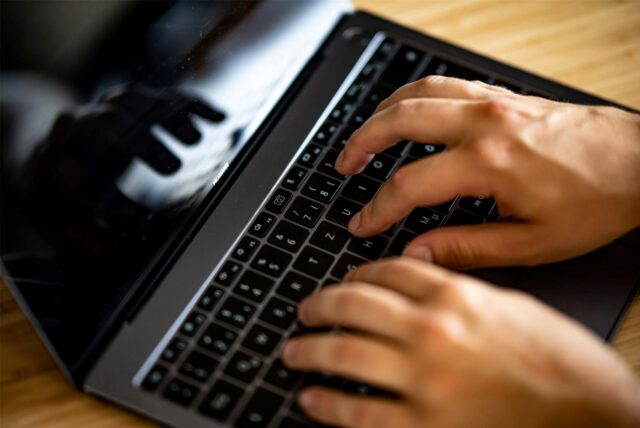 Ein Mann tippt auf der Tastatur eines Laptops.
