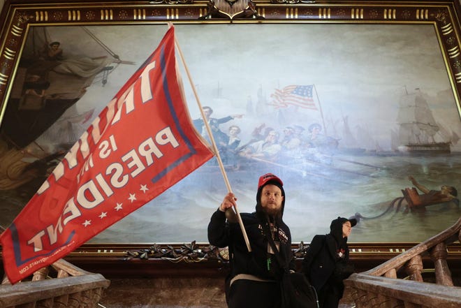 A protester holds a Trump flag inside the US Capitol near the Senate Chamber on January 06, 2021, after a violent mob overwhelmed police and stormed the building.