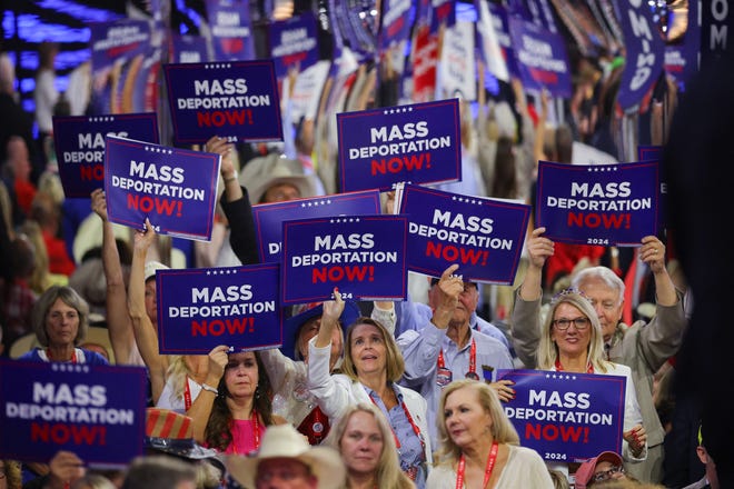 Delegates hold "MASS DEPORTATION NOW" signs at the Republican National Convention in Milwaukee on July 17, 2024.