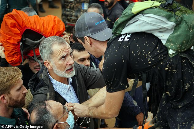 King Felipe VI of Spain (L) talks with a person as angry residents heckle him during his visit to Paiporta
