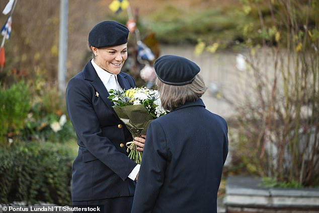 Victoria completed her ensemble with a simple white blouse, and carried a bouquet of white, yellow and blue flowers