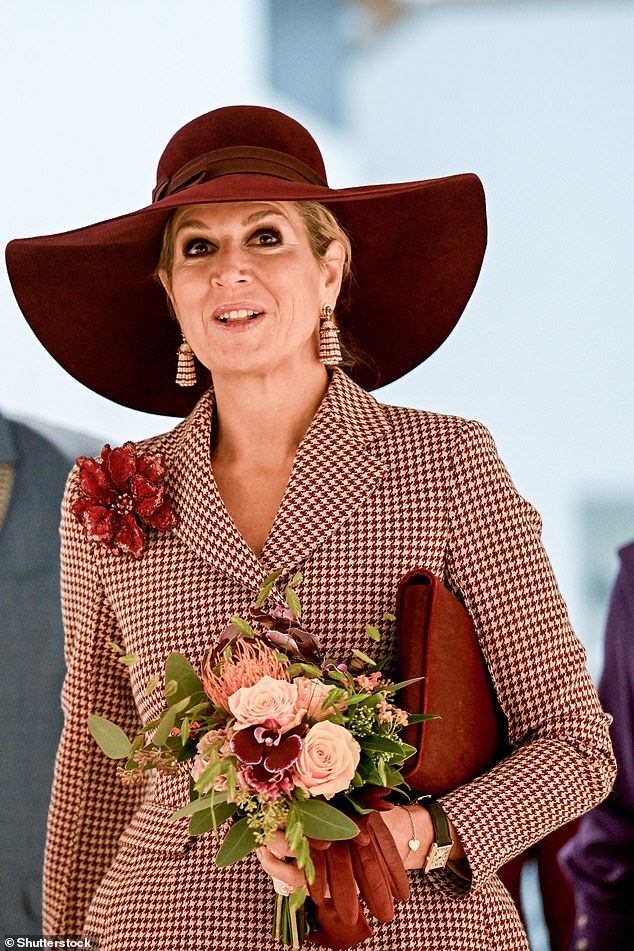 She wore a set of chic gold earrings and a blood red broach in the shape of a coneflower
