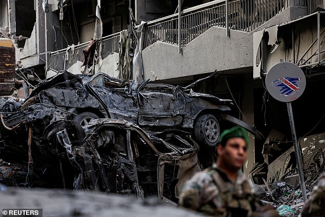 A Lebanese army soldier stands guard near damaged vehicles at the site of an Israeli strike