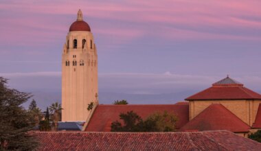 Hoover Tower above sandstone buildings, purple and pink sky in the background