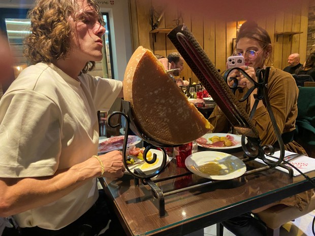 Heated Raclette cheese is scraped off for dipping into vegetables at Le Chalet Savoyard, a Paris restaurant specializing in fondue and other cheese dishes. (Janet Podolak - For The News-Herald)